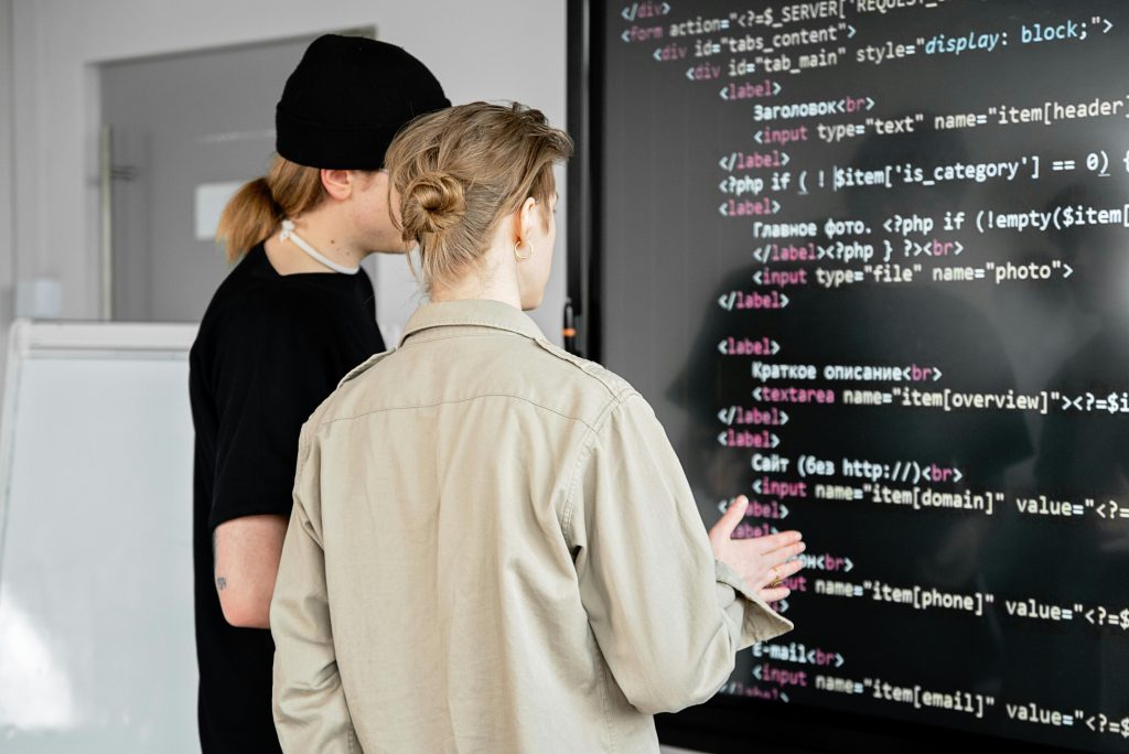 pexels-photo-7988747-7988747 Two developers examining code on a large screen in a modern office space, focusing on web development.