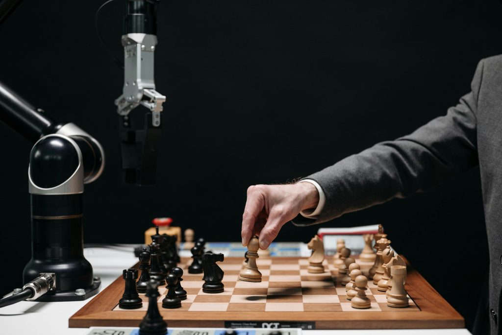 pexels-photo-8438944-8438944 A robotic arm plays chess against a human, symbolizing AI innovation and strategy.